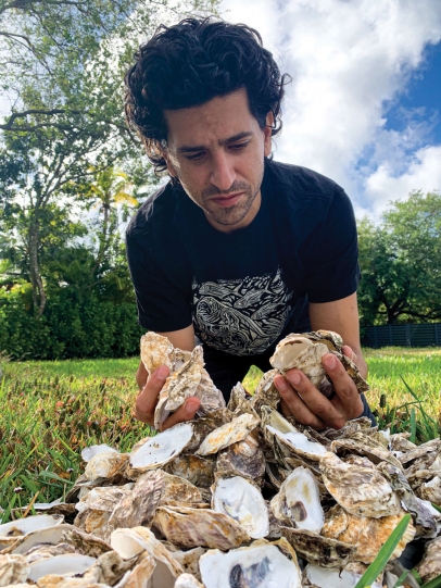 Tico Aran examines some of the discarded 25,000 oyster shells gathered from Michael’s Genuine and Kush Hospitality and spread outdoors to cure.