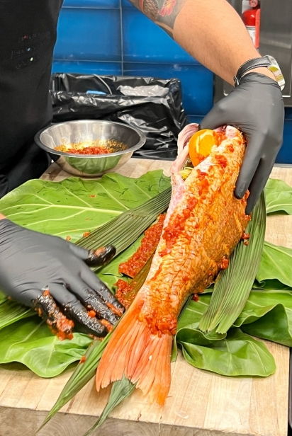 Chef Alex Diax rubbed whole fish with harissa paste before wrapping it in leaves to prepare it for the grill